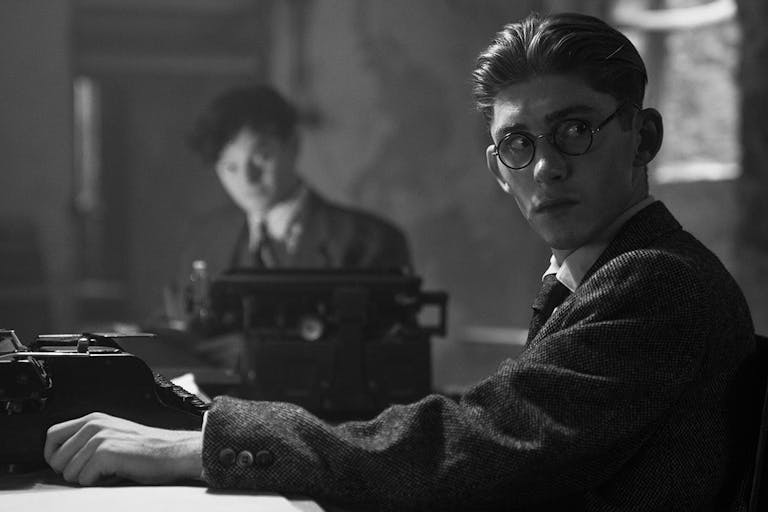 Black and white still of two young white men in 30s suit attire at a typewriters