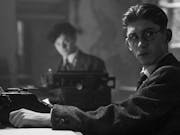 Black and white still of two young white men in 30s suit attire at a typewriters