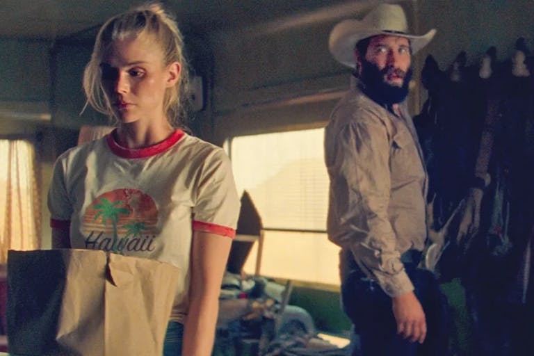 A young white woman holding a grocery bag looking scared as a white man in cowboy hat and country clothing stands behind her
