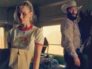 A young white woman holding a grocery bag looking scared as a white man in cowboy hat and country clothing stands behind her