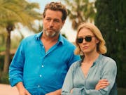 A white man in light blue shirt and white woman in pale blue shirt and sunglasses stand in a palm beach location looking serious
