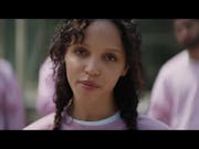 A young mixed heritage Black woman in a pink sweatshirt looking to camera