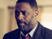 Black man with beard, wearing a suit and tie looking concerned