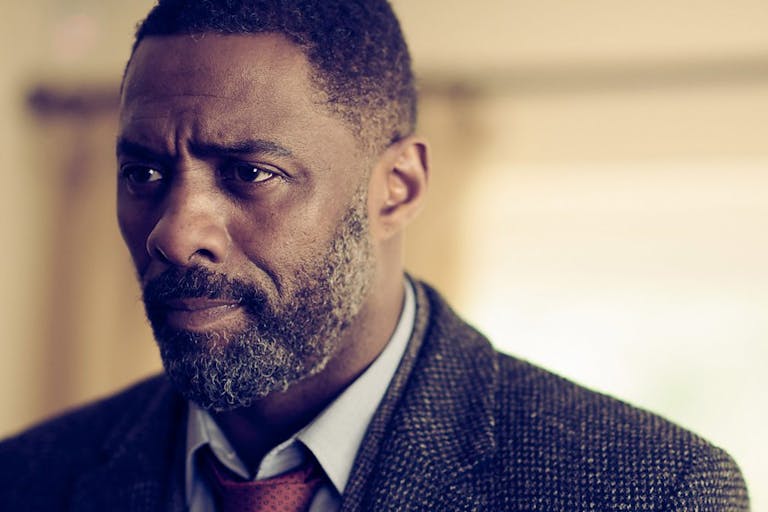 Black man with beard, wearing a suit and tie looking concerned