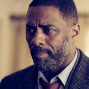 Black man with beard, wearing a suit and tie looking concerned