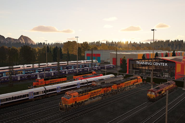 A train depot with a number of orange trains ready to leave the station.  In the background, the sun is setting behind green tree-covered hills