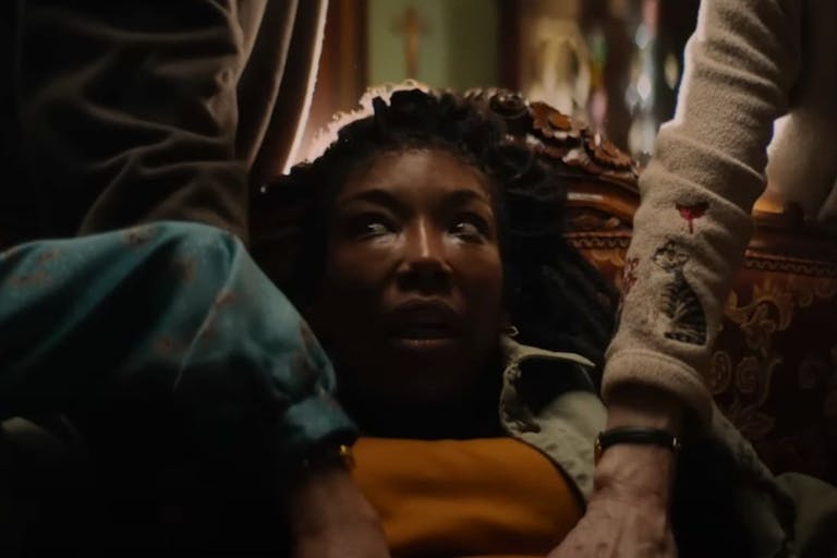 A black woman with long hair looking distressed as she is being grabbed by different hands