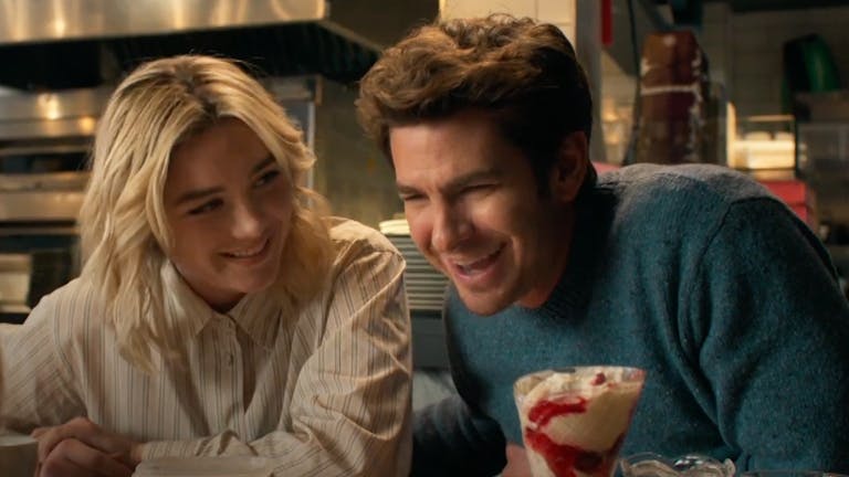 A young white woman and a young white man sitting at a table laughing