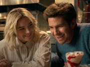 A young white woman and a young white man sitting at a table laughing