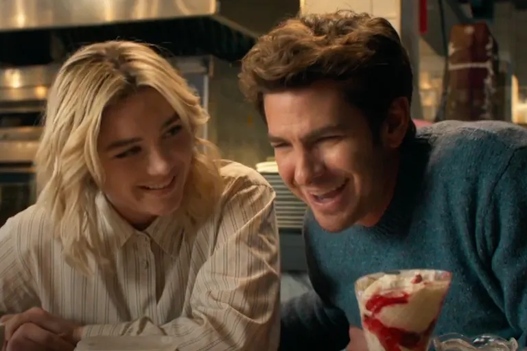 A young white woman and a young white man sitting at a table laughing