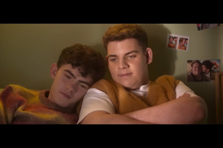 Two teen boys, one with his head on the other's shoulder, looking content