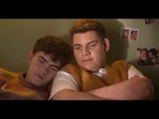 Two teen boys, one with his head on the other's shoulder, looking content