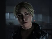 Gameplay of a shadowy dark room with a white woman with blonde hair looking concerned