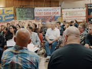 A room full of people having a community meeting with union and strike banners lining the room