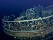 A large shipwrecked boat covered in barnacles underwater