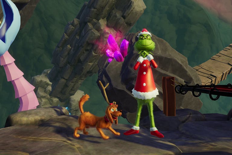 Gameplay of the Grinch, mischievous furry green figure in a red Santa outfit with his brown dog at this feet wearing one antler, standing on a dark stony mountain 