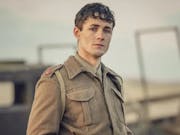 A young white male solider of WWII standing looking haunted