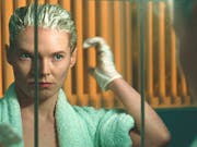 A woman is looking in a mirror to bleach her hair.