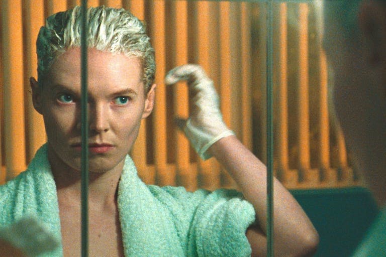 A woman is looking in a mirror to bleach her hair.