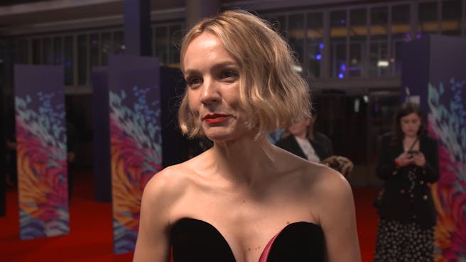 woman with short blonde hair in formal black strapless dress on the red carpet.