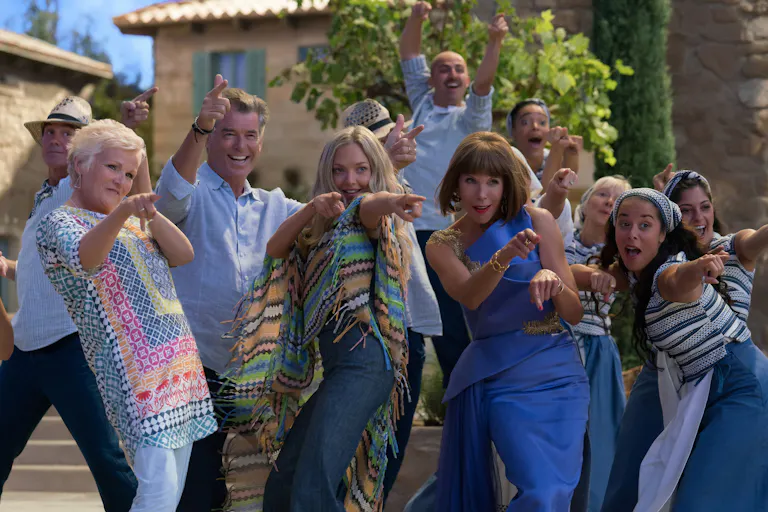 A group of people in Greece pointing and dancing