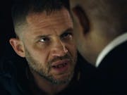 Close up of a white, tired and frustrated looking man talking to a Black man in a suit