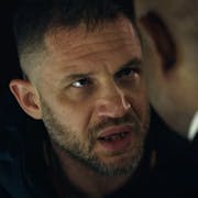 Close up of a white, tired and frustrated looking man talking to a Black man in a suit