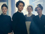 Four white woman in period clothes with their hair pulled up