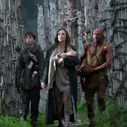 A white woman holding a baby next to a young white boy and an older white man covered in blood standing in front of pillars of bones