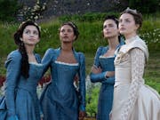 Four young women, three in blue elegant regency dresses and one in an ivory wedding dress