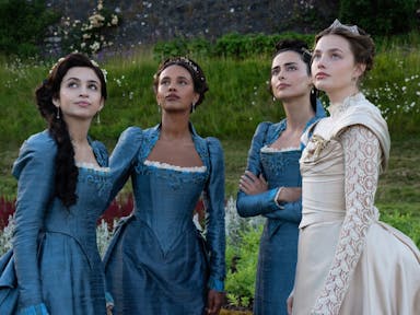 Four young women, three in blue elegant regency dresses and one in an ivory wedding dress