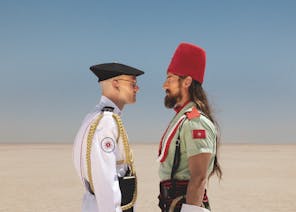 two men stare at each other in a desert