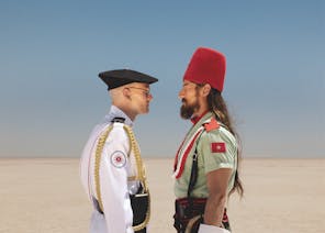 two men stare at each other in a desert