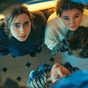 Three young white women, one holding a cat, looking a hole in the ceiling