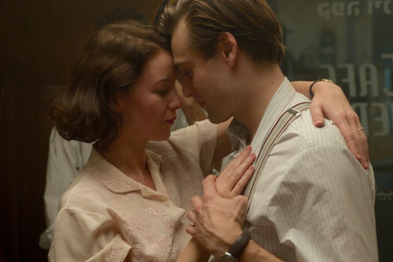 A young white woman and man in 1930s clothing, dancing closely and tenderly with their heads resting against each other