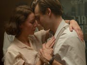 A young white woman and man in 1930s clothing, dancing closely and tenderly with their heads resting against each other