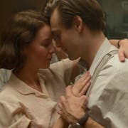 A young white woman and man in 1930s clothing, dancing closely and tenderly with their heads resting against each other