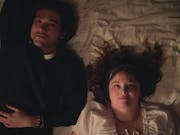 A British-Japanese young man and a white young woman lay on a bed looking up at the ceiling