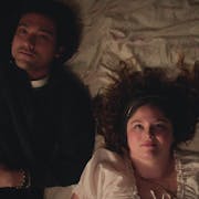 A British-Japanese young man and a white young woman lay on a bed looking up at the ceiling