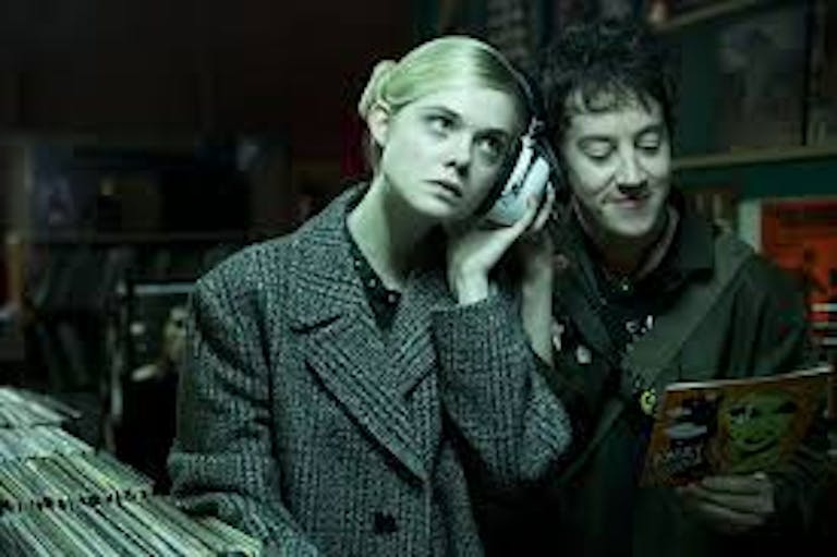 A blonde girl and a dark haired boy, listening to music near a collection of vinyl records