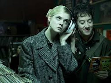 A blonde girl and a dark haired boy, listening to music near a collection of vinyl records