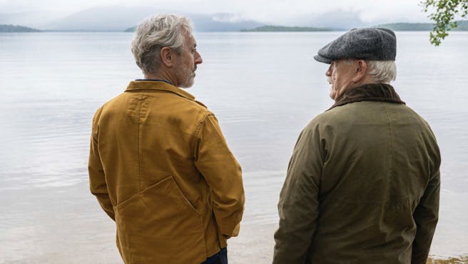 two older men look over a lake