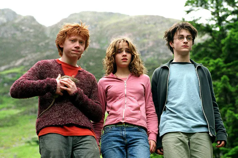 A ginger white teen boy holding a rat stands next to a white teen girl and a white teen boy wearing glasses with a scar on his forehead