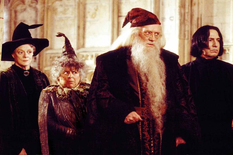 Four wizards with capes and hats looking towards the right of the screen