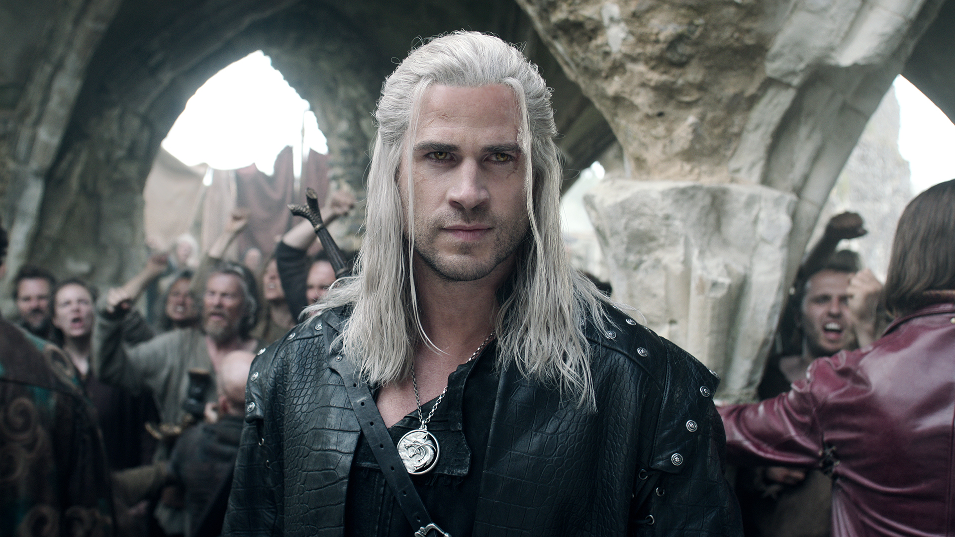 A white man with long white hair and hazel eyes, wearing black leather and a sword strapped to his back