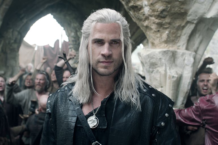 A white man with long white hair and hazel eyes, wearing black leather and a sword strapped to his back