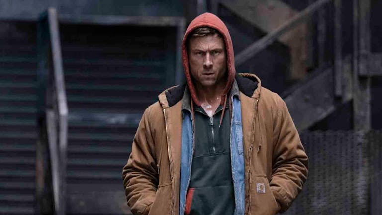 A young white man in a shirt, hoodie and coat looking angry and determined