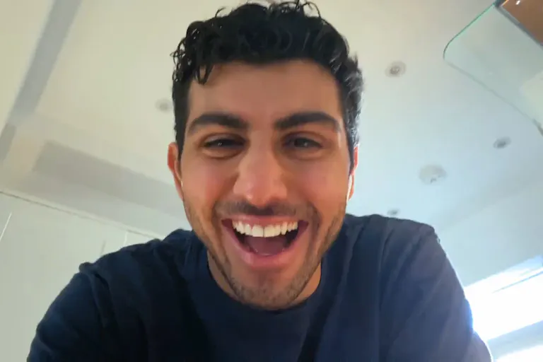 A man is looking at the camera for a higher angle. He has a wide smile on his face.