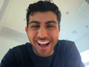 A man is looking at the camera for a higher angle. He has a wide smile on his face.