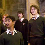 A young group of students in jumpers, ties and robes standing inside a grand castle